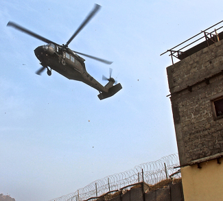 A U.S. Army UH-60 Black Hawk helicopter prepares to land as U.S. soldiers provide security from a building window at the Khyber Border Coordination Center near Torkham Gate at the Afghanistan-Pakistan border in Afghanistan's Nangarhar province, Jan. 4, 2015.