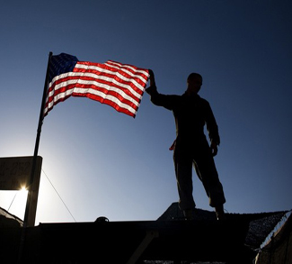 A U.S. Marine from 3rd Battalion 4th Marines, adjusts the U.S. flag on the top of his tent on base Delaram in Nimroz province
