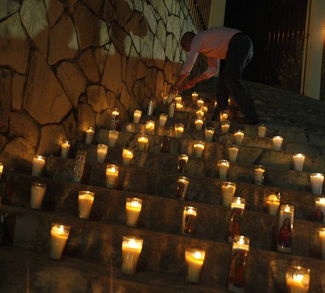 A resident lights a candle on the steps of a church in memory of Edelmiro Cavazos, mayor of the tourist town of Santiago