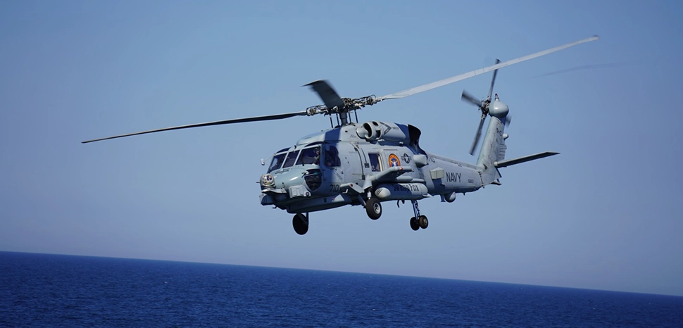 210617-N-NO901-0004 BALTIC SEA (June 17, 2021) An MH-60R Sea Hawk helicopter attached to the “Swamp Foxes” of Helicopter Maritime Strike Squadron (HSM) 74 flies by the Arleigh Burke-class guided-missile destroyer USS Thomas Hudner (DDG 116), June 17, 2021 during exercise BALTOPS 50. BALTOPS 50 is an annual international maritime-led joint exercise including 16 NATO allies and 2 partner nations demonstrating the ability of the alliance to contribute to deterring and if required defeating aggression. (U.S. Navy photo by U.S. Thomas Hudner Public Affairs/Released) cc Flickr, modified, https://www.flickr.com/photos/cne-cna-c6f/51257091333/