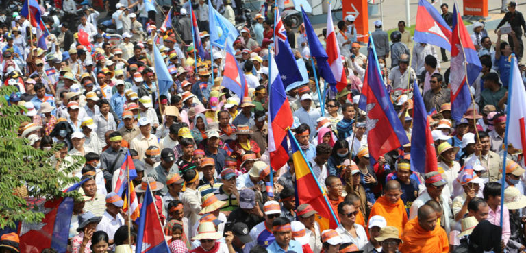Opposition supporters wave national flags of some Western countries who were signatory parties to the 22 year old Paris Peace Agreement, Phnom Penh, Oct 24, 2013. (Heng Reaksmey/VOA Khmer), cc Heng Reaksmey, modified, https://commons.wikimedia.org/w/index.php?title=Special:Search&redirs=0&search=cambodia%20CNRP&fulltext=Search&ns0=1&ns6=1&ns14=1&title=Special:Search&advanced=1&fulltext=Advanced%20search#/media/File:CNRP_protesters_raise_flags.jpg
