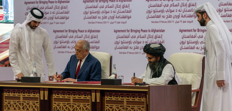 US representative Zalmay Khalilzad (left) and Taliban representative Abdul Ghani Baradar (right) sign the agreement in Doha, Qatar on February 29, 2020. [State Department photo by Ron Przysucha/ Public Domain], cc US State Department, modified,