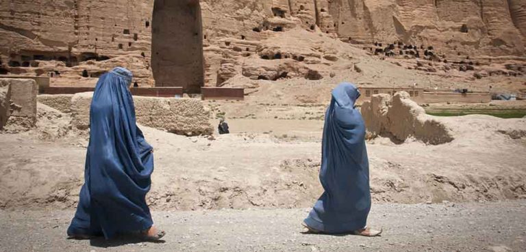 Two women walk past the huge cavity where one of the ancient Buddhas of Bamiyan, known to locals as the 