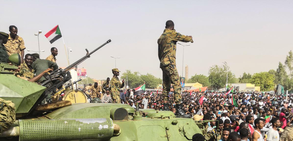 English: Sudanese soldeirs stand guard around armoured military vehicles as demonstrators continue their protest against the regime near the army headquarters in the Sudanese capital Khartoum, cc Agence France-Presse, modified, https://commons.wikimedia.org/wiki/File:Sudan_coup_military_afp.jpg