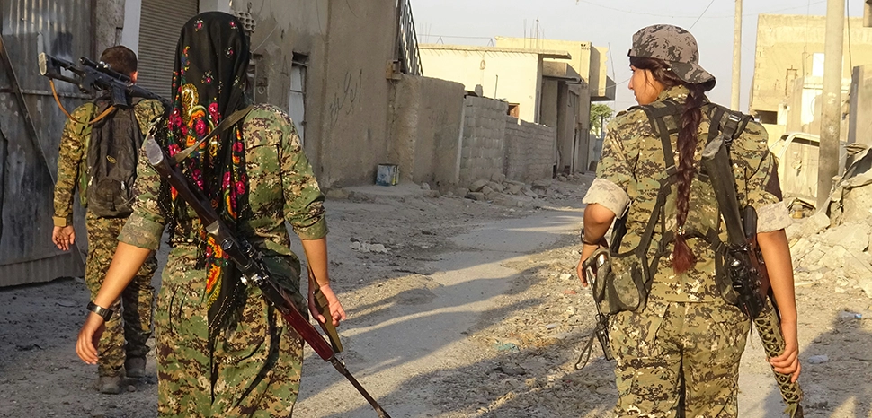                 cc Kurdishstruggle, modified, Two YPJ fighters and a YPG fighter with rifles over their backs / https://commons.wikimedia.org/wiki/File:Two_YPJ_fighters_and_a_YPG_fighter_with_rifles_over_their_backs.jpg
              